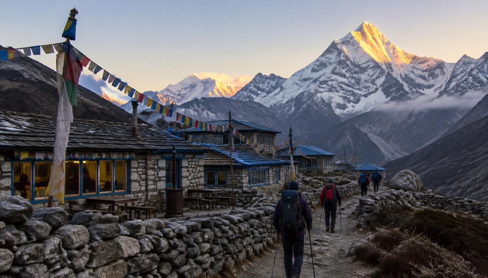 Stone teahouses below Himalayan peaks at dawn